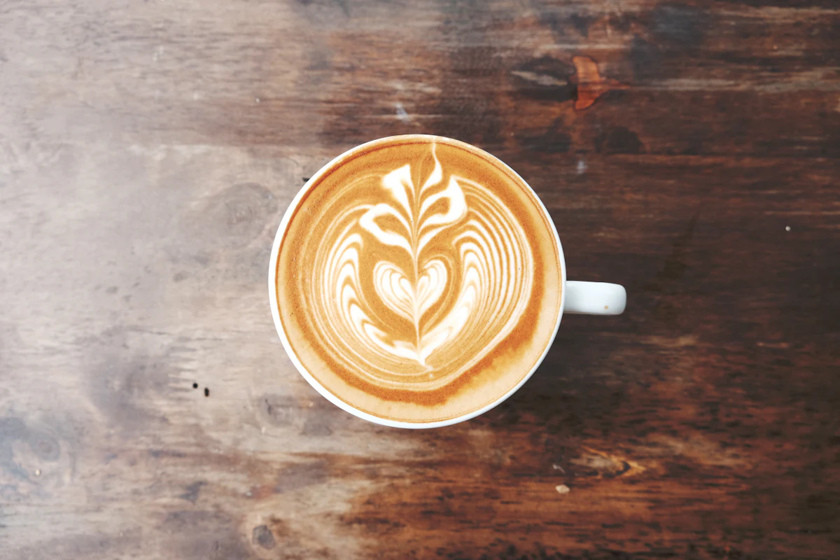 Flat white con arte latte servido sobre una superficie de madera